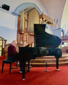 man playing a grand piano in a church Sanctuary